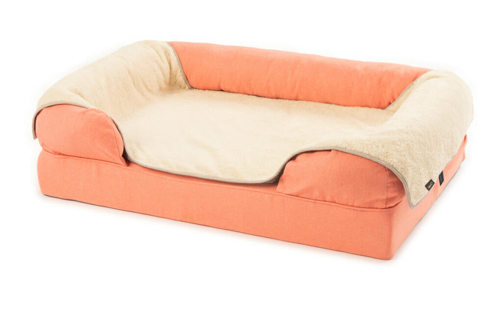 Een groot 42 roze traagschuim bolster bed met een crèmekleurige pluche deken er overheen