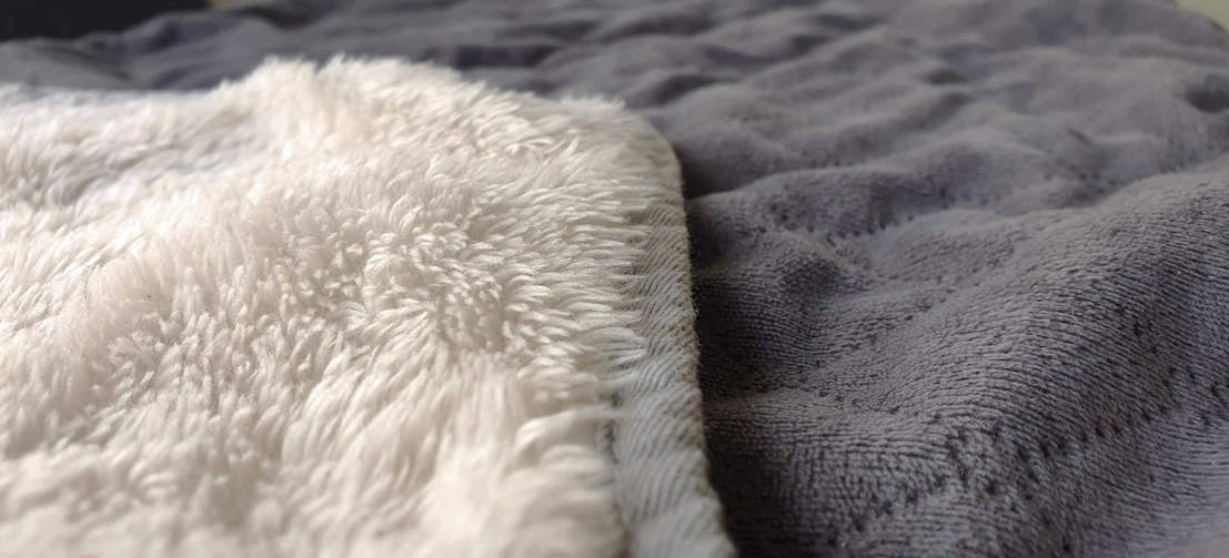 Het deken is dubbelzijdig met aan de ene kant een stijlvol gestikte grijze kleur en een luxe crème fleece katoen aan de andere kant