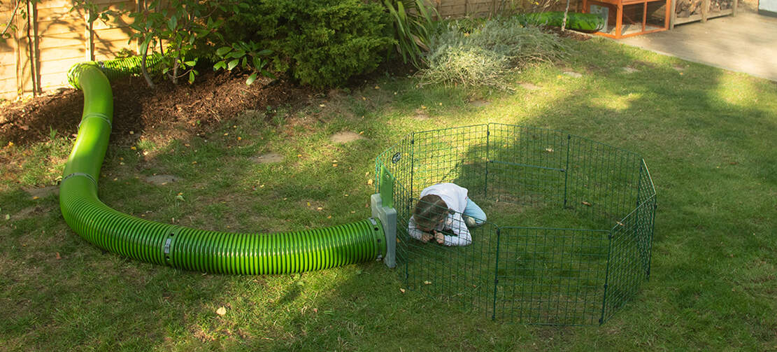 Kid playing in Omlet Zippi rabbit playpen that has a Omlet Zippi tunnel connected