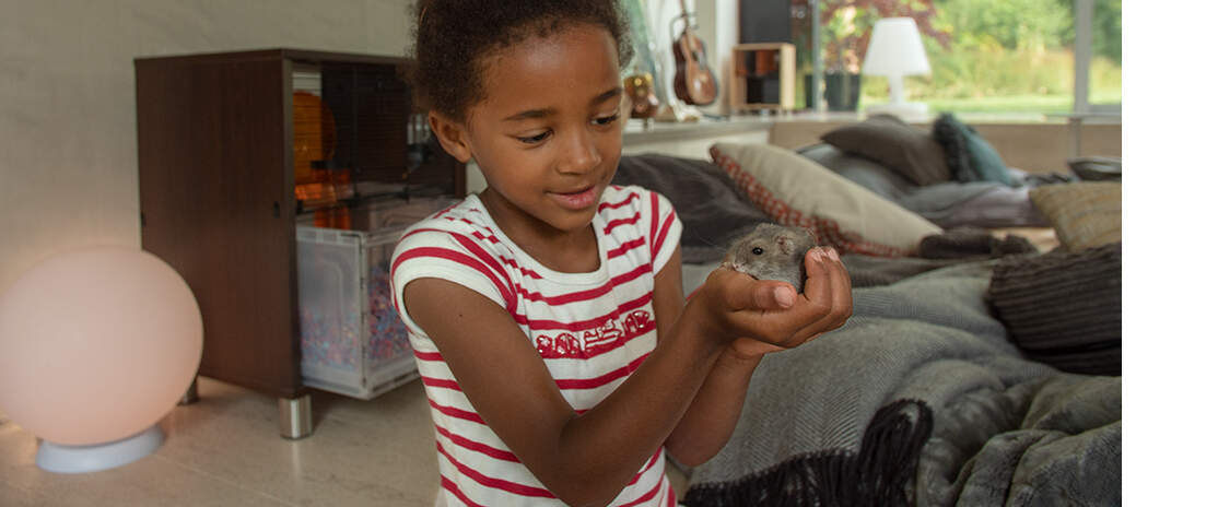 En flicka som håller en hamster framför en hamster Qute