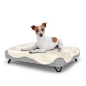 Hund sitzt auf einem kleinen Topology hundebett mit schafsfellauflage und schwarzen metall-haarnadelfüßen