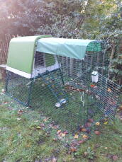 A green coop and run installed in a garden