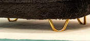 Une image en gros plan des pieds de l'épingle à cheveux Gold sur le lit pour chat earl grey donut