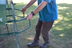 A person demonstrating how to use the handles in order to move their chicken coop