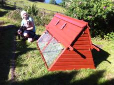 A customer and her dog proudly posing next to their red wooden chicken coop