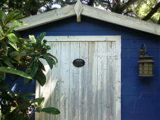 a large blue painted wooden chicken coop with a beware of the chickens sign