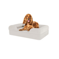 Pies siedzący na średnim bezowym leGowisku dla psa z białej pianki memory foam bolster