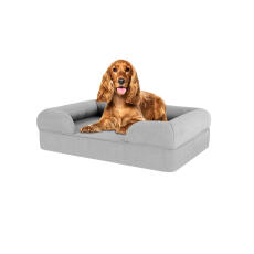 Pies siedzący na średnim, szarym leGowisku dla psa z pianki memory foam