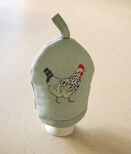 An eggcup with an egg cosy on it.