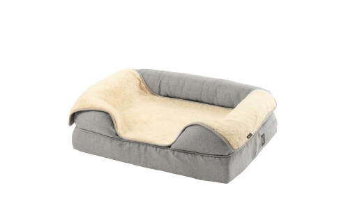 Un lit à traversin en mousse à mémoire de forme gris avec une couverture en peluche crème par-dessus