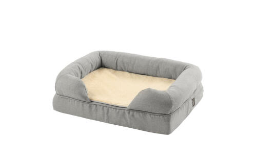 Un lit à traversin en mousse à mémoire de forme gris avec une couverture en peluche pliée au milieu