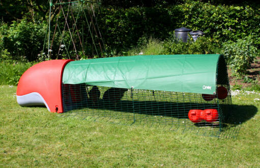 Röd Eglu Classic hönshus med löpning och grönt skydd i full längd som ger skugga i trädgården