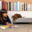 Cane seduto su Omlet Topology letto del cane con topper trapuntato e piedi di rotaia nera indagando ragazze libro