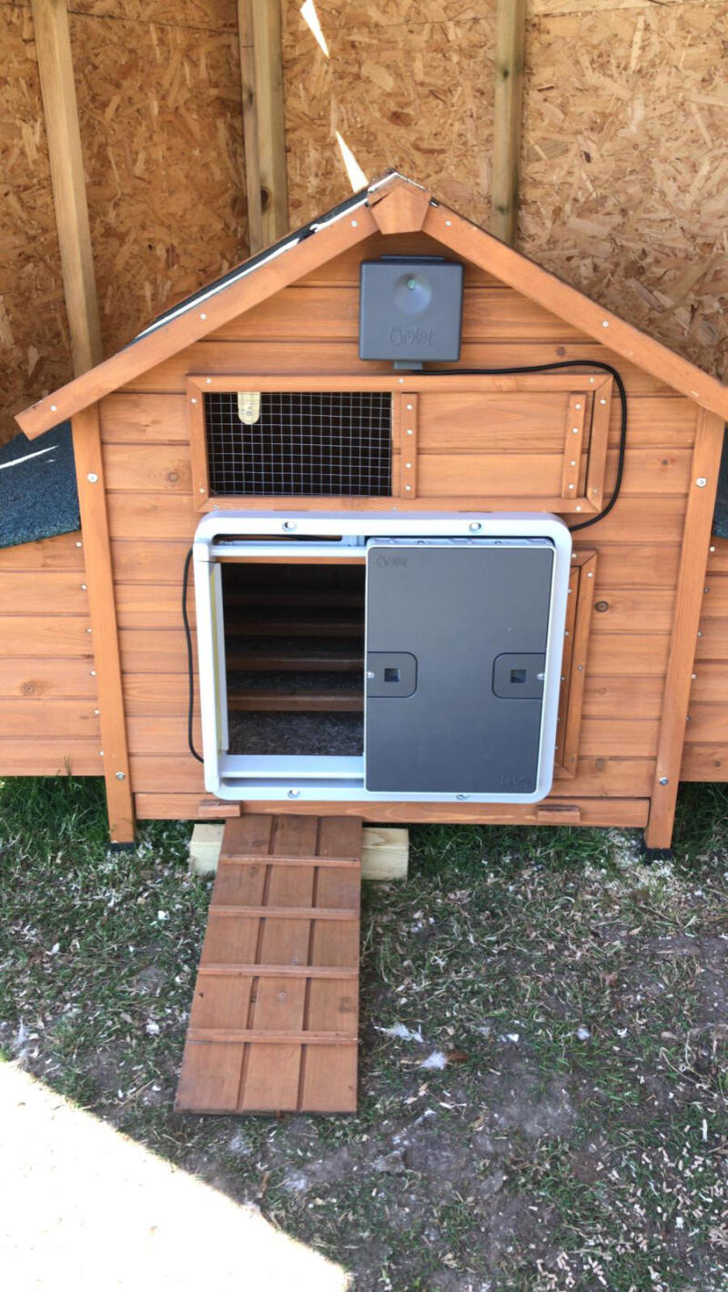 A grey automatic door mounted on a wooden coop