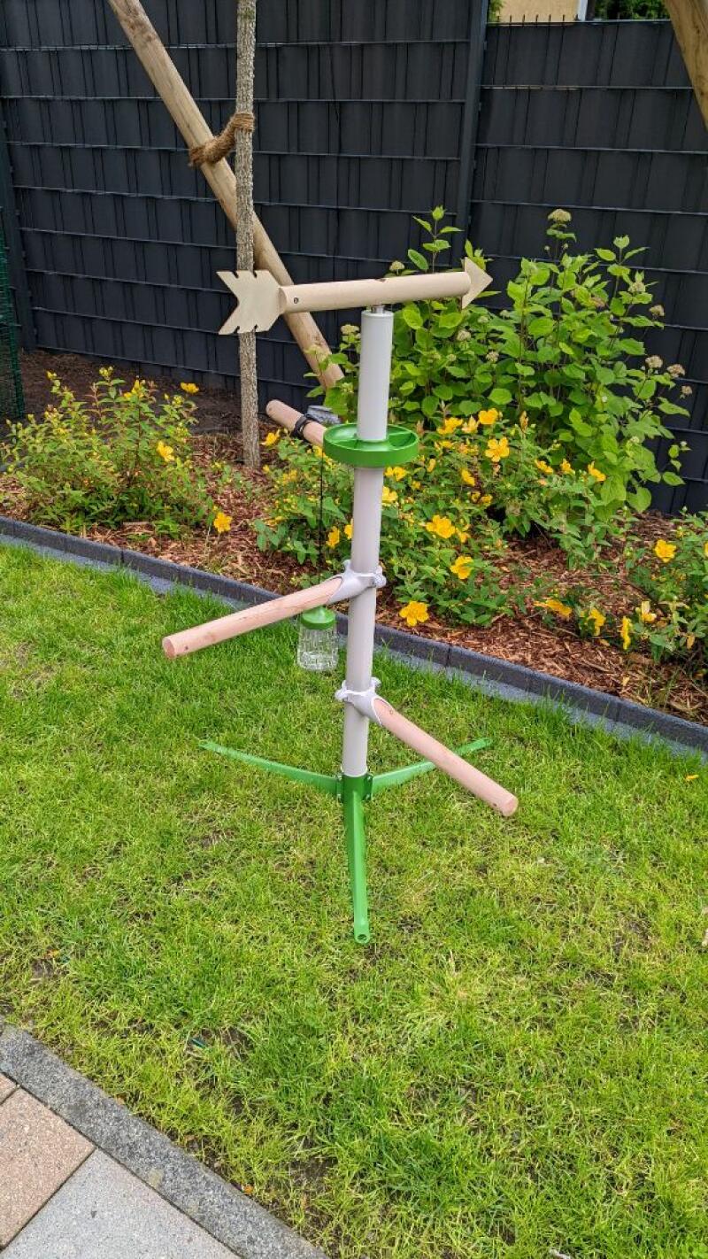 A free standing pole with chicken perches and a weathervane