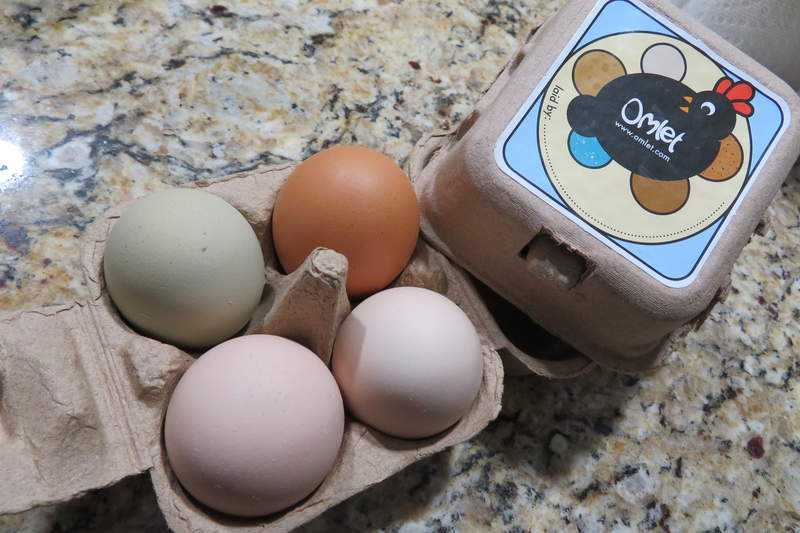 Een Omlet eierdoos met vier verschillende kleuren eieren erin.