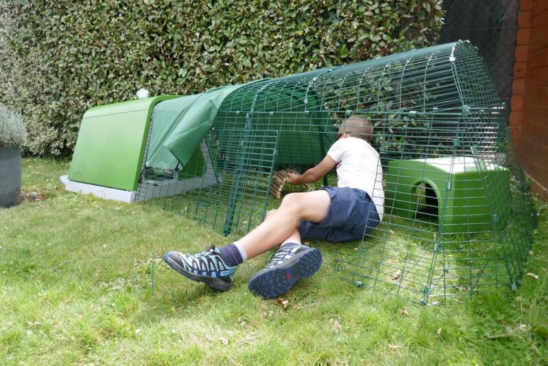 En person som visar hur man rengör en kaninbana som är ansluten till en grön bur.