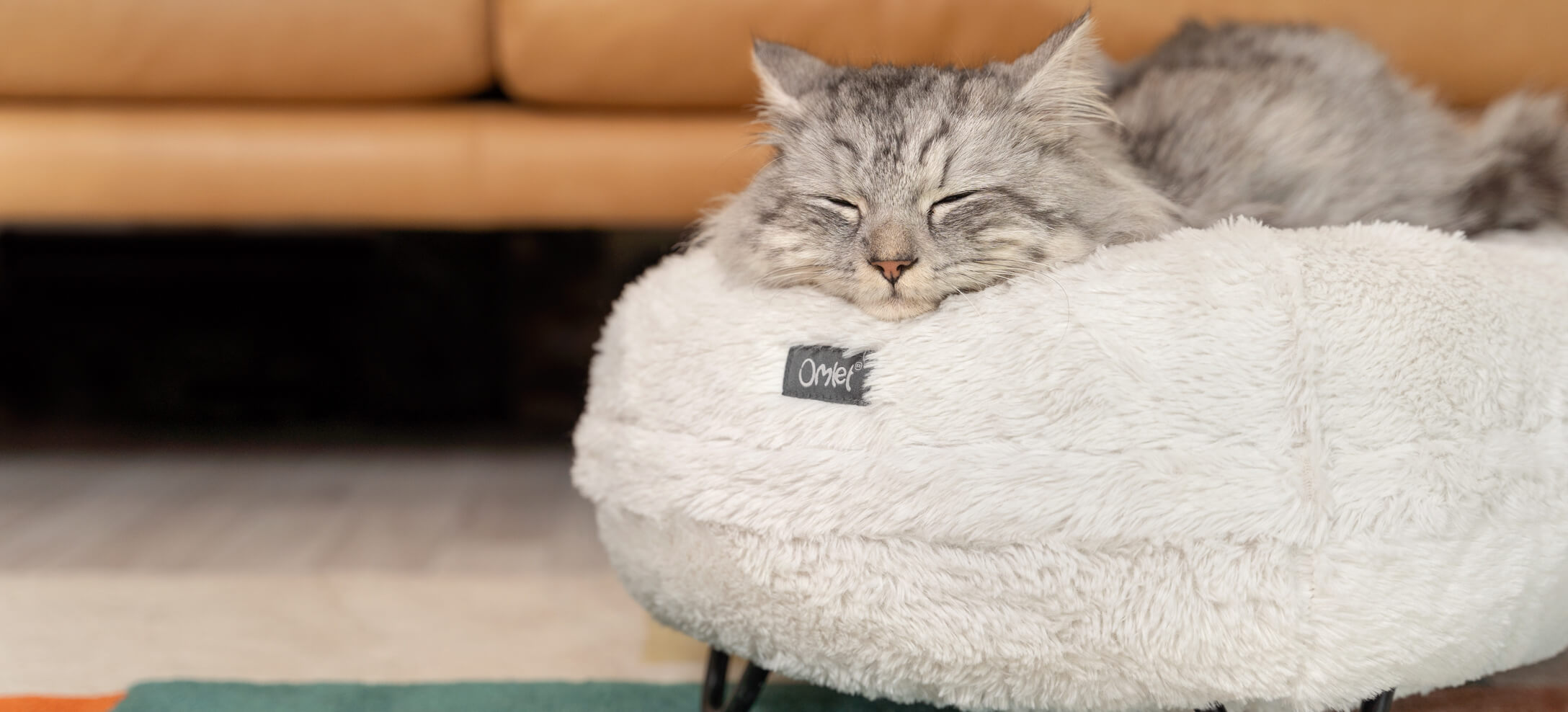 Un chat gris qui dort sur un lit pour chat Maya Donut blanc