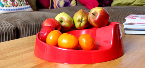  En rød Rollabowl frugtskål på et sofabord.