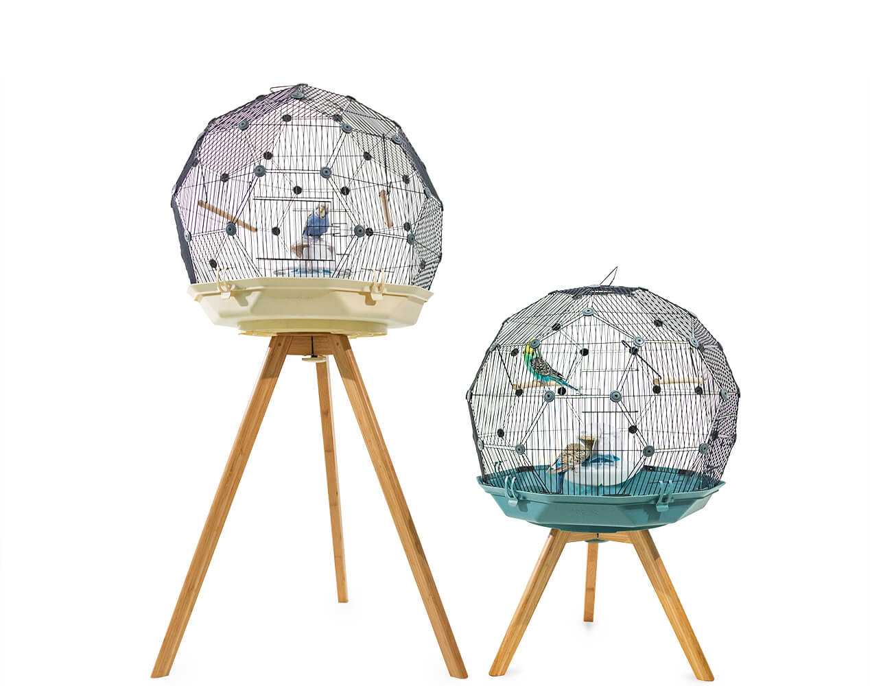 A Geo Bird Cage in cream on a standard height wooden bird cage stand next to a Geo Bird cage in teal on a low height wooden bird cage stand