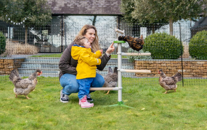 Mutter und Tochter spielen im Garten mit ihren Hühnern