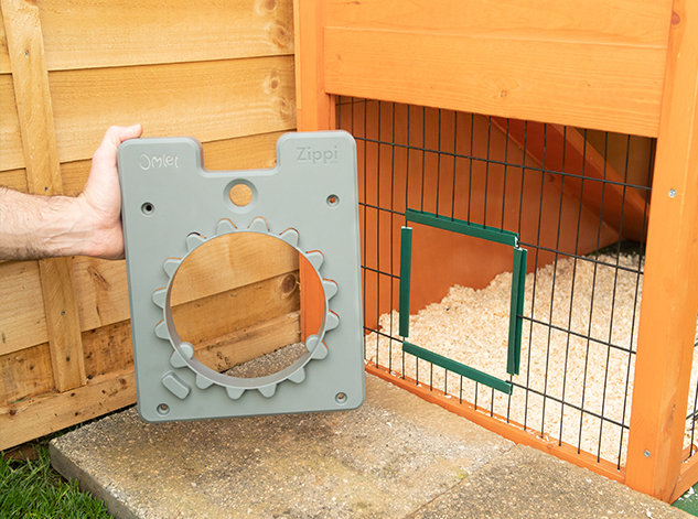 man attaching the guinea pig tunnel door frame to a hutch's wire mesh
