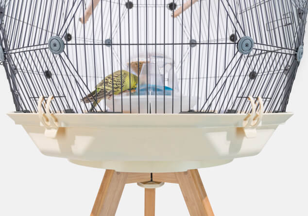 The Geo Bird Cage on a wooden stand with a cream coloured base