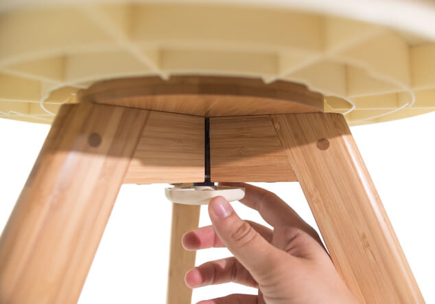 A close up of someone screwing the base of the Geo Budgie Cage securely onto a wooden bird cage stand